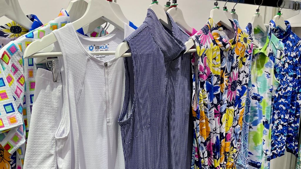 Collection of colorful women's golf dresses displayed on hangers showing various styles and patterns