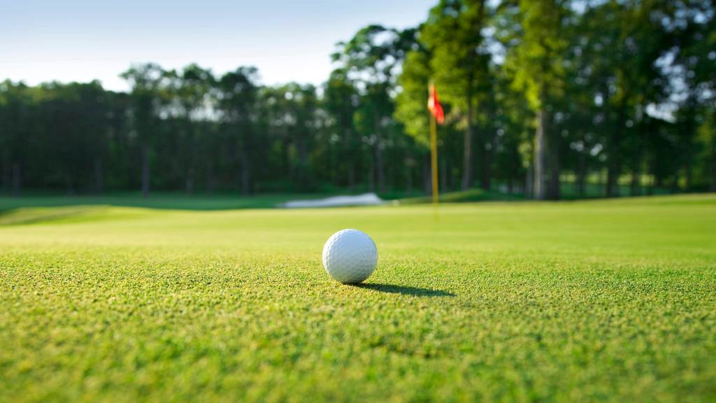 golf ball rolling on sloped putting green
