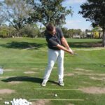 Golfer practicing swing technique on driving range to improve form and accuracy